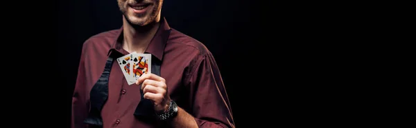 KYIV, UCRAINA - 20 AGOSTO 2019: colpo panoramico di uomo barbuto felice con carte da gioco isolate su nero — Foto stock