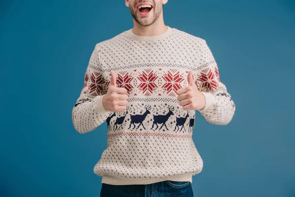 Vista recortada del hombre excitado en suéter de invierno que muestra los pulgares hacia arriba aislado en azul - foto de stock
