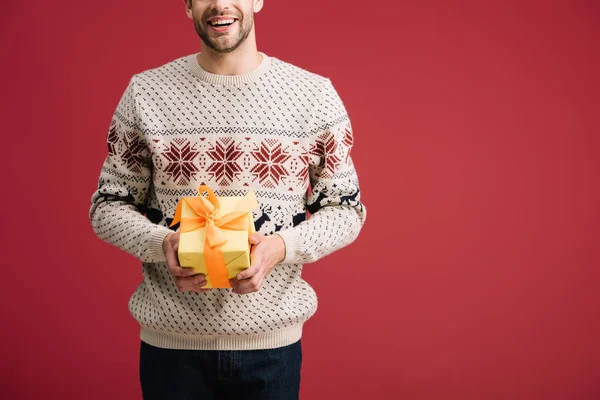 Recortado vista de sonriente hombre sosteniendo regalo aislado en rojo - foto de stock