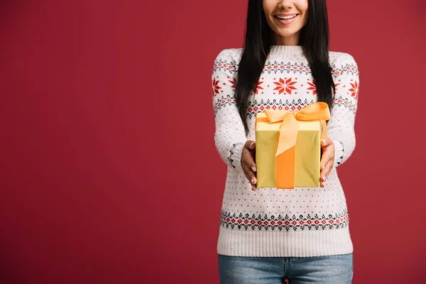 Recortado vista de hermosa mujer sosteniendo regalo de Navidad aislado en rojo - foto de stock