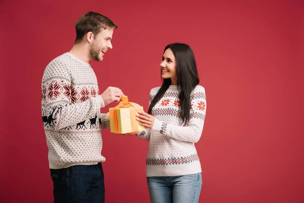 Feliz pareja con la Navidad presente aislado en rojo - foto de stock