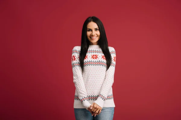 Lächelndes Mädchen posiert in Winterpullover isoliert auf Rot — Stockfoto