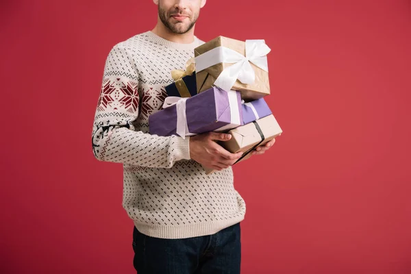 Vue recadrée de l'homme tenant boîtes cadeaux de Noël isolé sur rouge — Photo de stock