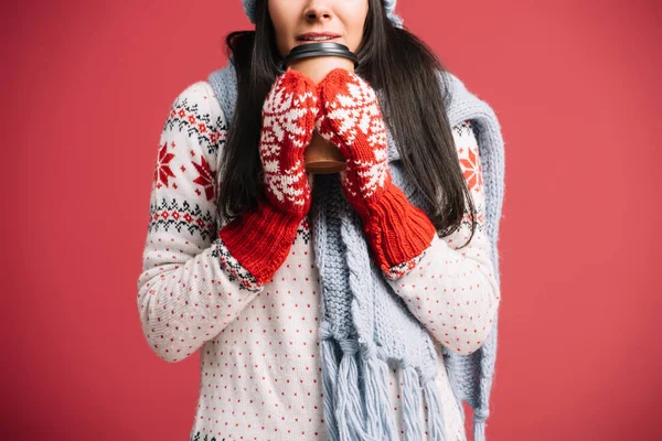 Cropped view of woman in winter scarf and mittens holding coffee to go, isolated on red — Stock Photo