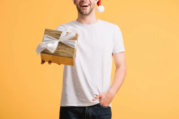 Vista ritagliata di felice uomo in cappello di Babbo Natale tenuta presente isolato su giallo — Foto stock
