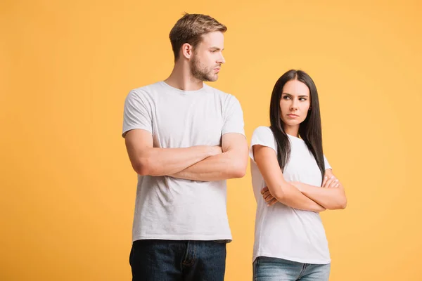 Offended couple standing with crossed arms, isolated on yellow — Stock Photo
