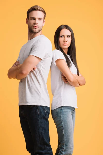 Ображена пара, що стоїть спиною до спини з схрещеними руками, ізольована на жовтому — стокове фото