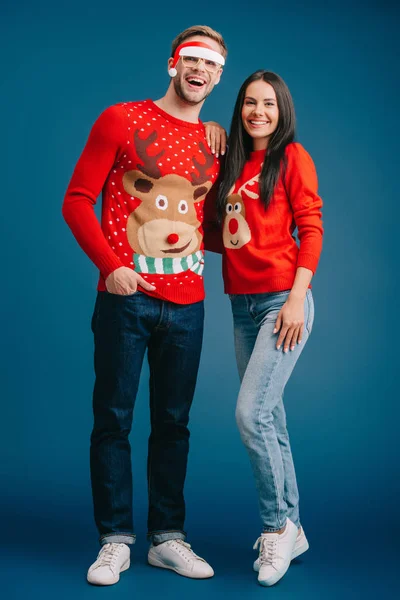 Glücklicher Mann mit Brille und Weihnachtsmann umarmt Frau isoliert auf blauem Grund — Stockfoto