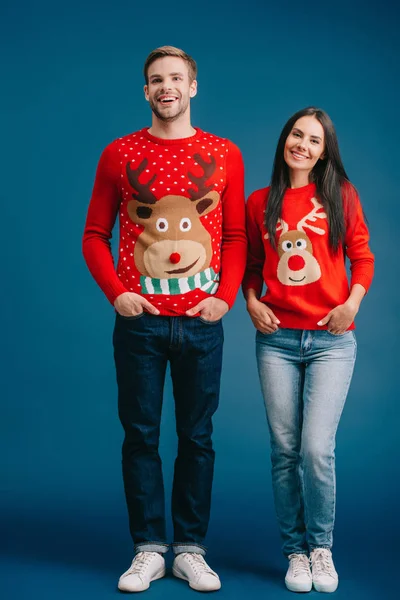 Happy couple posing in christmas sweaters isolated on blue — Stock Photo