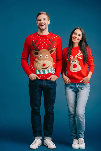 Casal feliz posando em camisolas de Natal isolado em azul — Fotografia de Stock