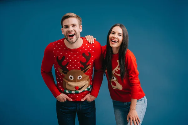 Ridere coppia posa in maglioni di Natale isolato su blu — Foto stock