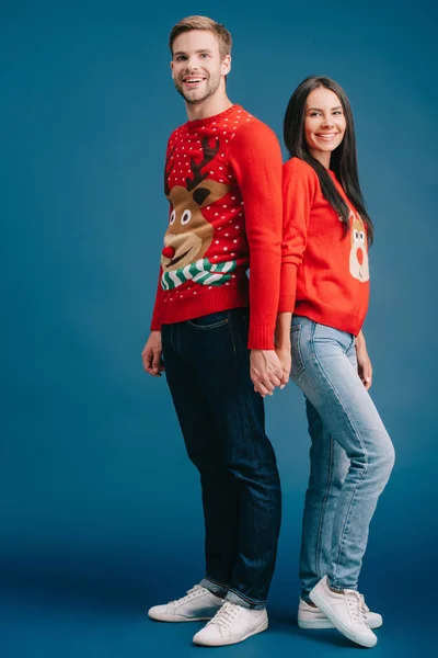 Casal feliz em camisolas de Natal de mãos dadas isoladas em azul — Fotografia de Stock