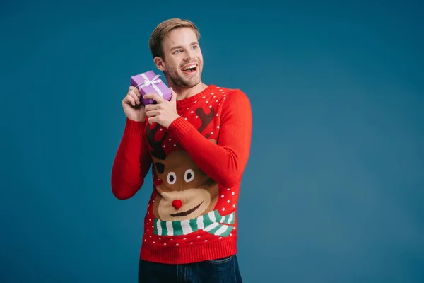 Glücklicher Mann im Pullover hält Weihnachtsgeschenk isoliert auf gelb — Stockfoto