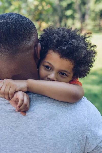 Adorável afro-americano menino abraçando pai enquanto caminhava no parque — Fotografia de Stock