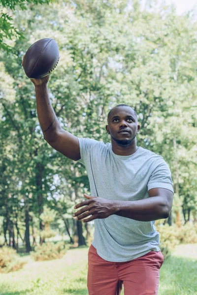 Sport uomo africano americano in esecuzione con la palla da rugby nel parco — Foto stock