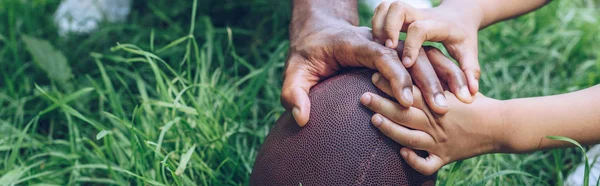 Partial view of african american father and son touching rugby ball, panoramic shot — Stock Photo