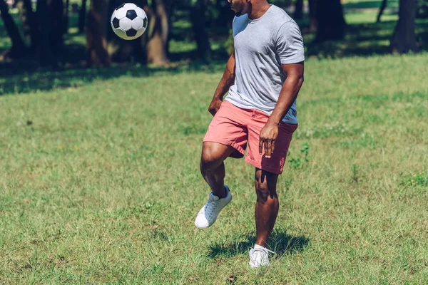 Обрізаний вид спорту афроамериканський чоловік грає у футбол у парку — стокове фото