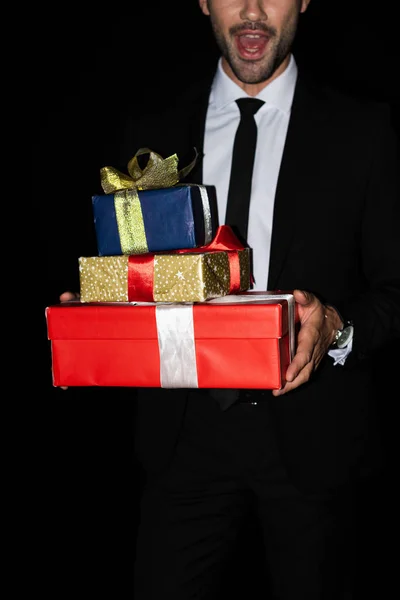 Vista cortada de homem animado segurando caixas de presente, isolado em preto — Fotografia de Stock