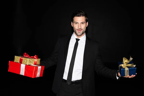 Счастливый человек, держащий подарочные коробки, изолированные на черном — стоковое фото