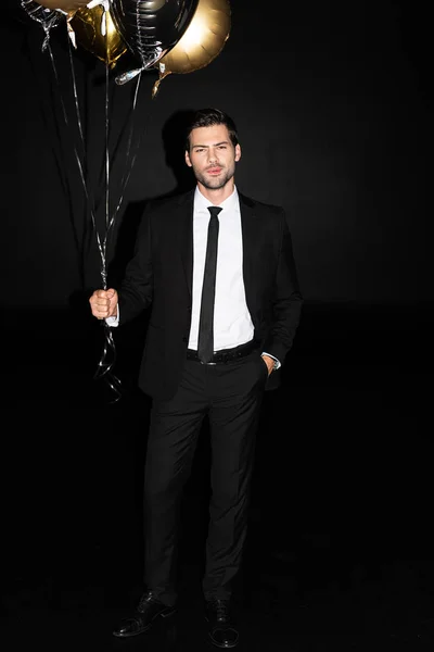 Uomo elegante con palloncini d'oro, isolato su nero — Foto stock