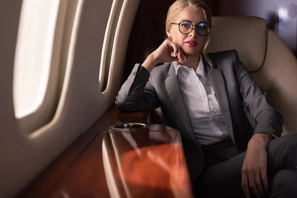 Attractive female manager sitting in plane during business trip — Stock Photo