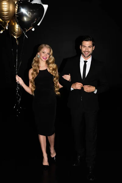 Hermosa pareja con globos de oro en partido aislado en negro - foto de stock