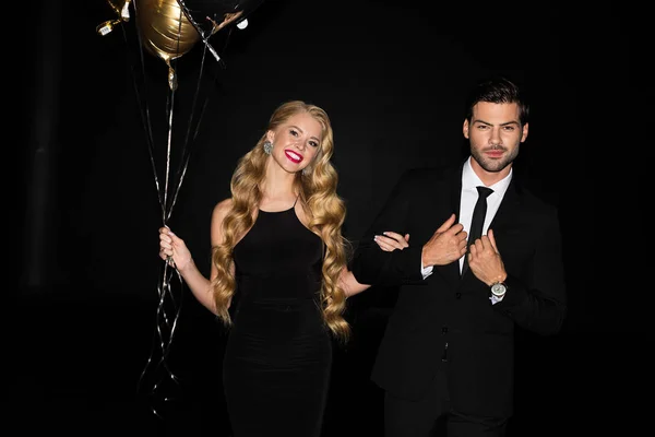 Happy couple with golden balloons on party isolated on black — Stock Photo