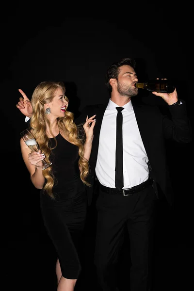 Beautiful cheerful couple celebrating and drinking champagne isolated on black — Stock Photo
