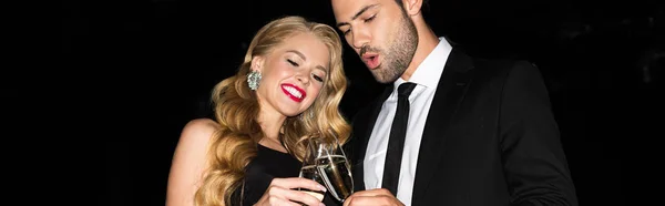 Feliz pareja tintineo con copas en champán aislado en negro - foto de stock