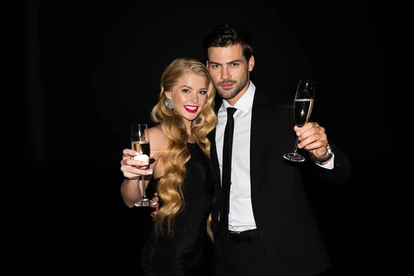 Beautiful happy couple celebrating with champagne isolated on black — Stock Photo