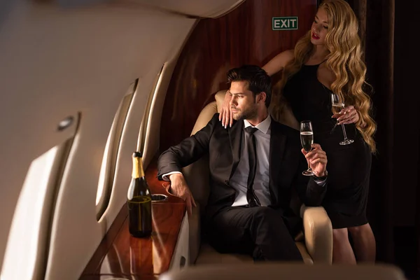 Élégant à la mode avec champagne voyageant en avion — Photo de stock