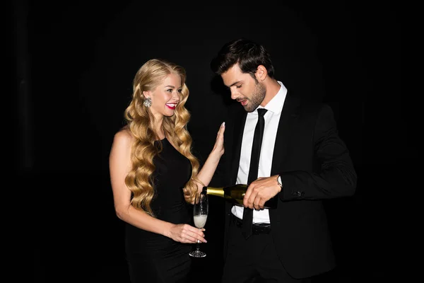 Beautiful couple celebrating with champagne isolated on black — Stock Photo