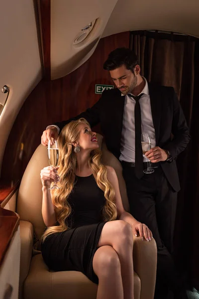 Beautiful elegant couple drinking champagne while traveling in plane — Stock Photo