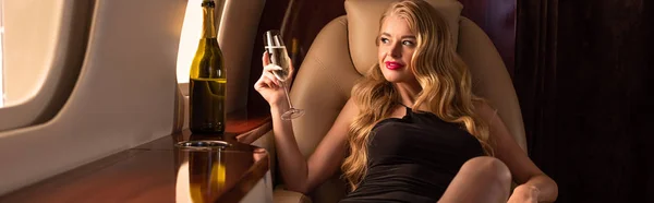 Hermosa mujer rubia con champán sentado en el avión - foto de stock