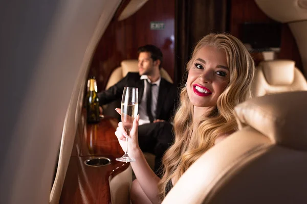 Selective focus of happy woman and man with champagne glass in plane — Stock Photo