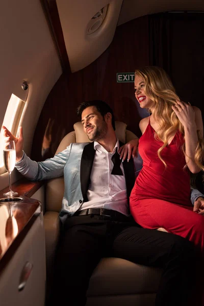 Atractiva mujer y hombre con champán sentado en el avión - foto de stock