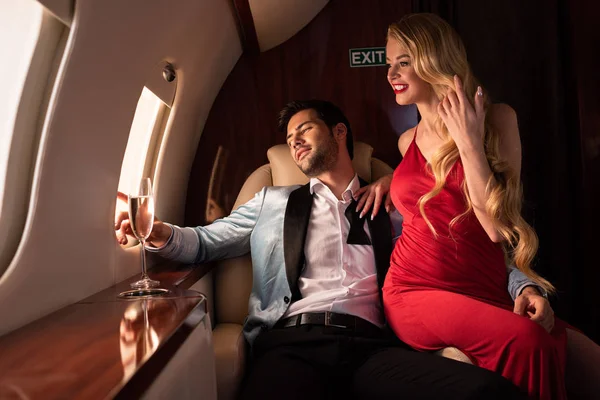 Hermosa pareja elegante con champán sentado en el avión - foto de stock