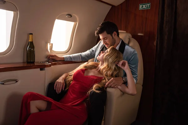 Sensual couple with champagne sitting in airplane — Stock Photo
