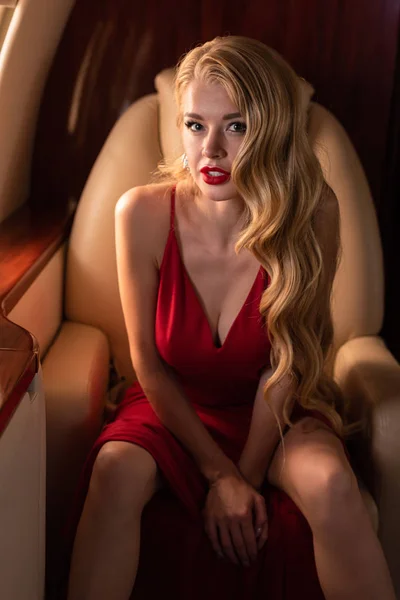 Mulher glamourosa apaixonado em vestido vermelho sentado no avião — Fotografia de Stock