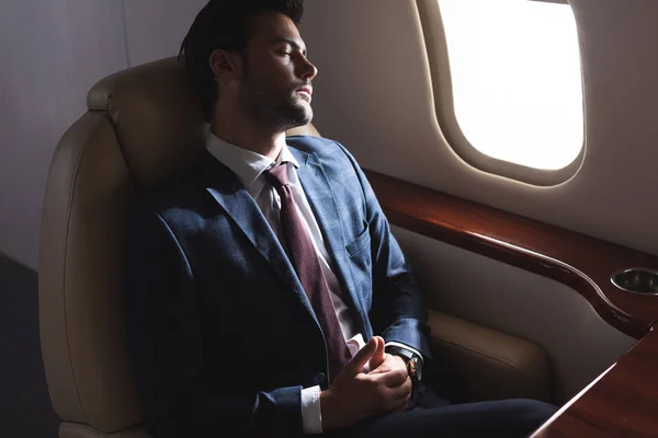 Businessman sleeping in airplane during business trip — Stock Photo