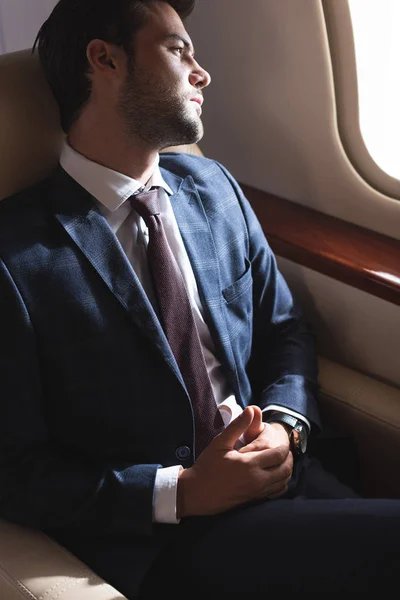 Pensive businessman looking into window in plane — Stock Photo