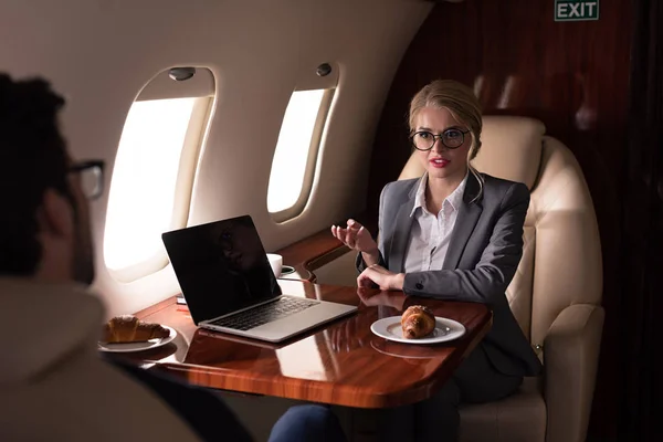 Professional business colleagues working with laptop in airplane — Stock Photo