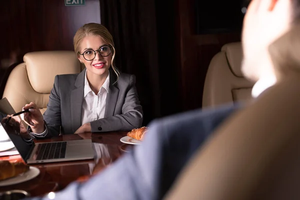 Selective focus of professional businesspeople working with laptop in plane — Stock Photo