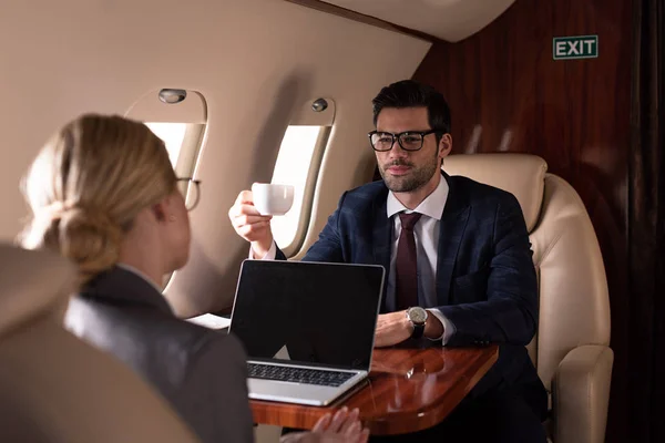 Executive professional businesspeople having meeting with laptop in plane — Stock Photo