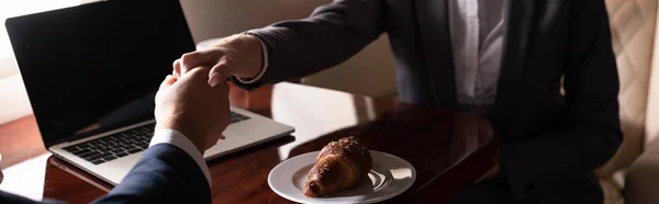 Cropped view of professional businesspeople shaking hands in plane with laptop — Stock Photo