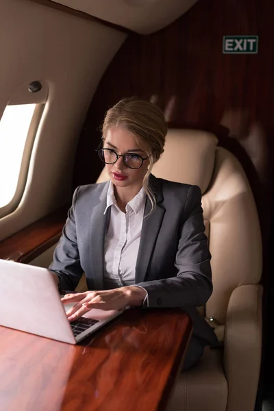 Mujer de negocios que trabaja en el ordenador portátil en avión durante su viaje de negocios - foto de stock