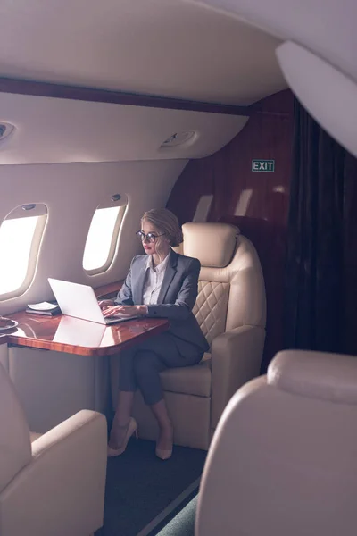 Mujer de negocios profesional que trabaja en el ordenador portátil en avión durante su viaje de negocios - foto de stock