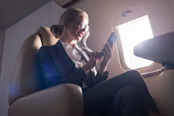 Donna d'affari preoccupata che parla su smartphone in aereo durante il viaggio di lavoro — Foto stock