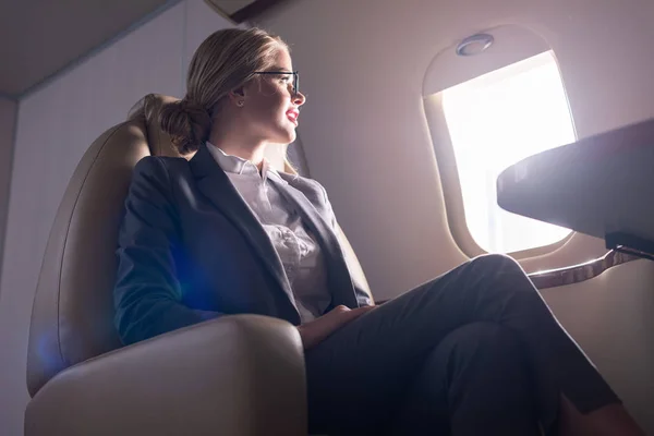 Attractive businesswoman in glasses sitting in plane during business trip — Stock Photo