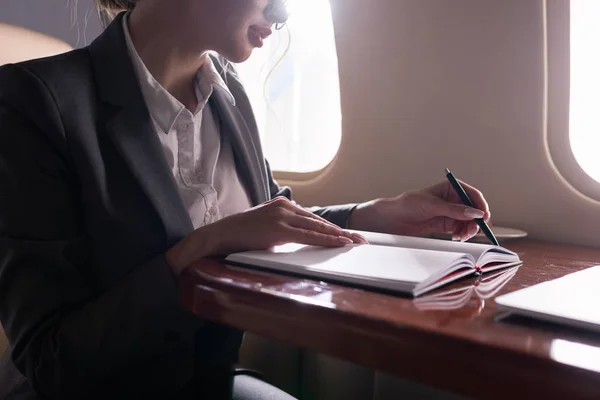 Cropped view of businesswoman working with documents in plane during business trip — Stock Photo